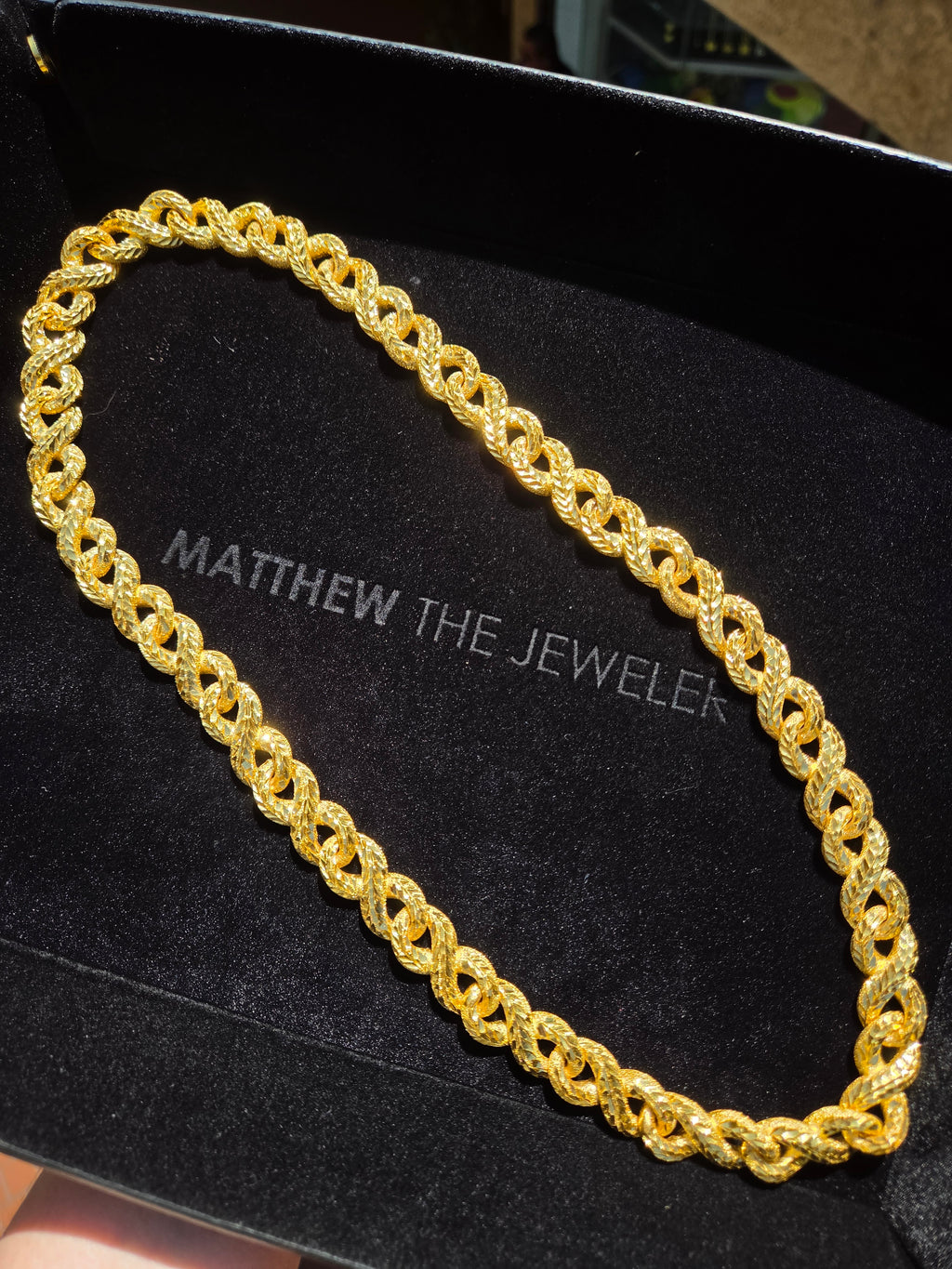 Diamond-Cut Infinity Link Chain in solid gold, mirror-cut faces catching the light against the matte frosted texture between them