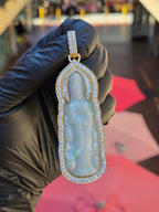 Jade Lady Buddha (Guan Yin) Round and Baguette Diamond Wrap Pendant in daylight, a carved jade plaque of Guan Yin standing on a lotus, framed in gold with round diamonds following the scalloped edge.