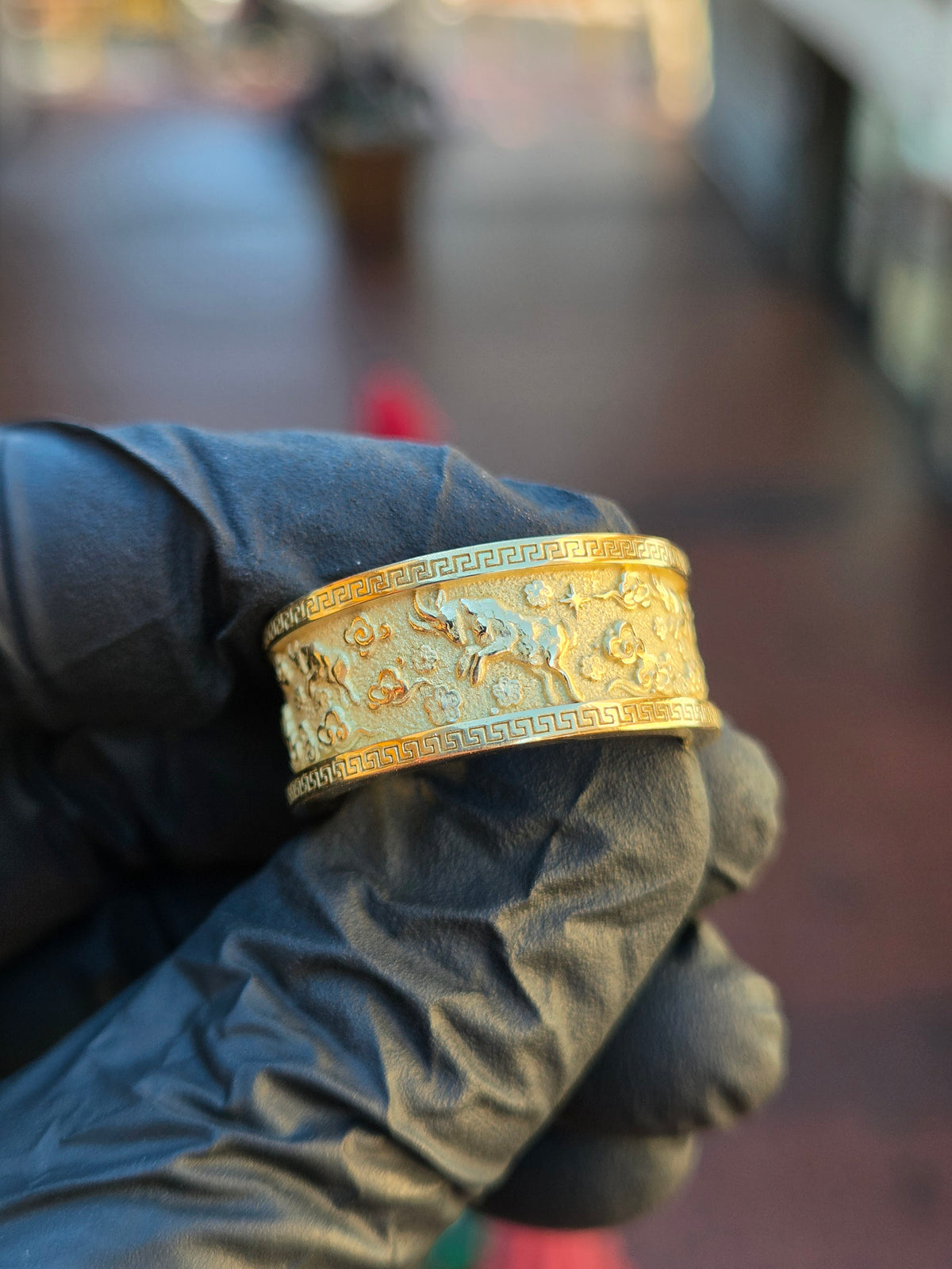Goat Mural Ring in yellow gold, angled view of the 10MM band showing goats and stylized clouds in raised relief between Greek key borders
