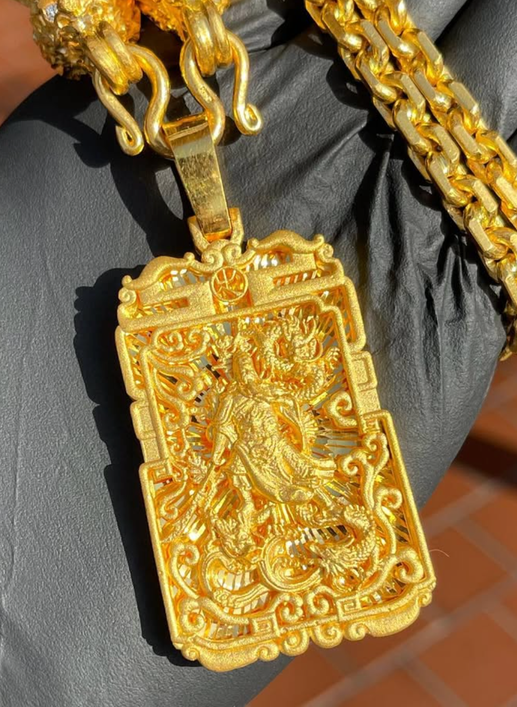 God of War and Dragon Fretwork gold pendant, angled view showing light passing through the pierced openwork ground