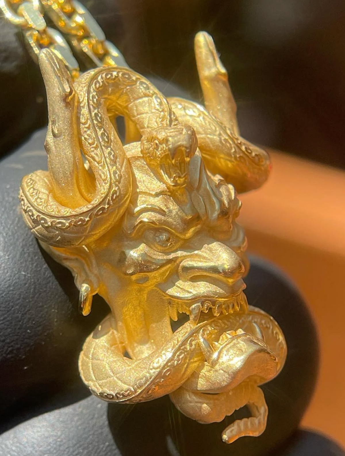 Hannya mask gold pendant, angled view showing the snake rearing between the horns