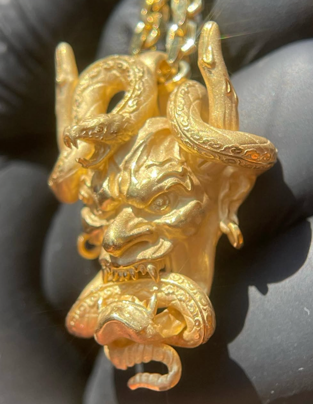 Hannya mask gold pendant detail, furrowed brow, bared fangs and coiled snake beneath the chin