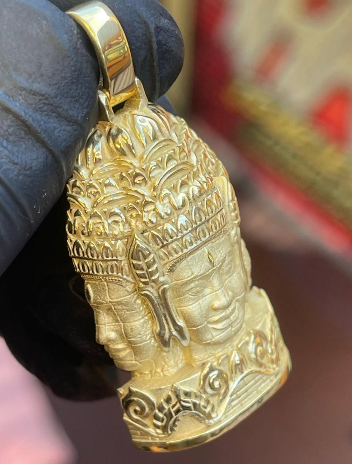 Bayon face tower gold pendant, angled view showing the stepped petal courses above the brow