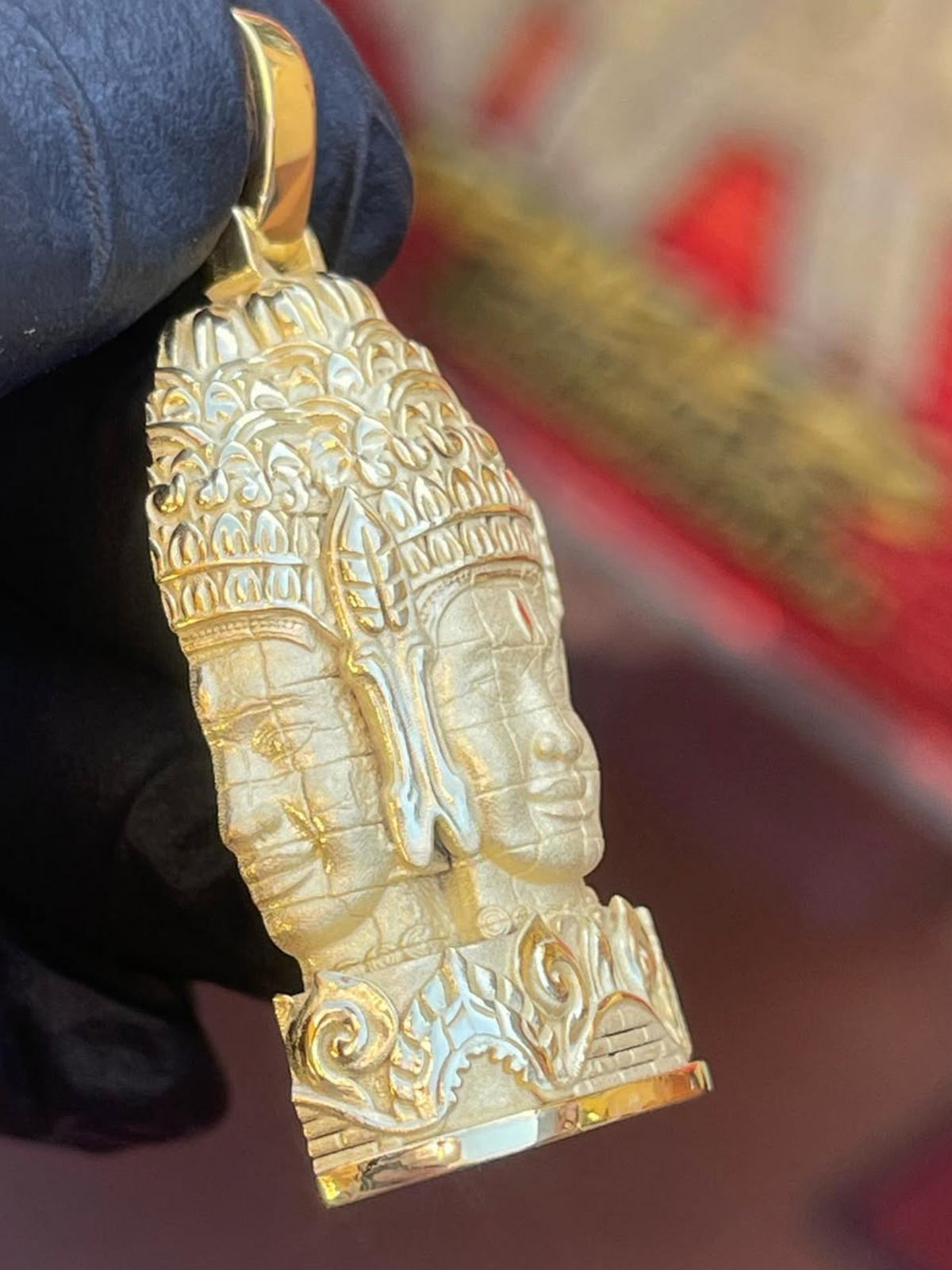 Bayon face tower gold pendant profile, second face turned to the side over kbach scrollwork