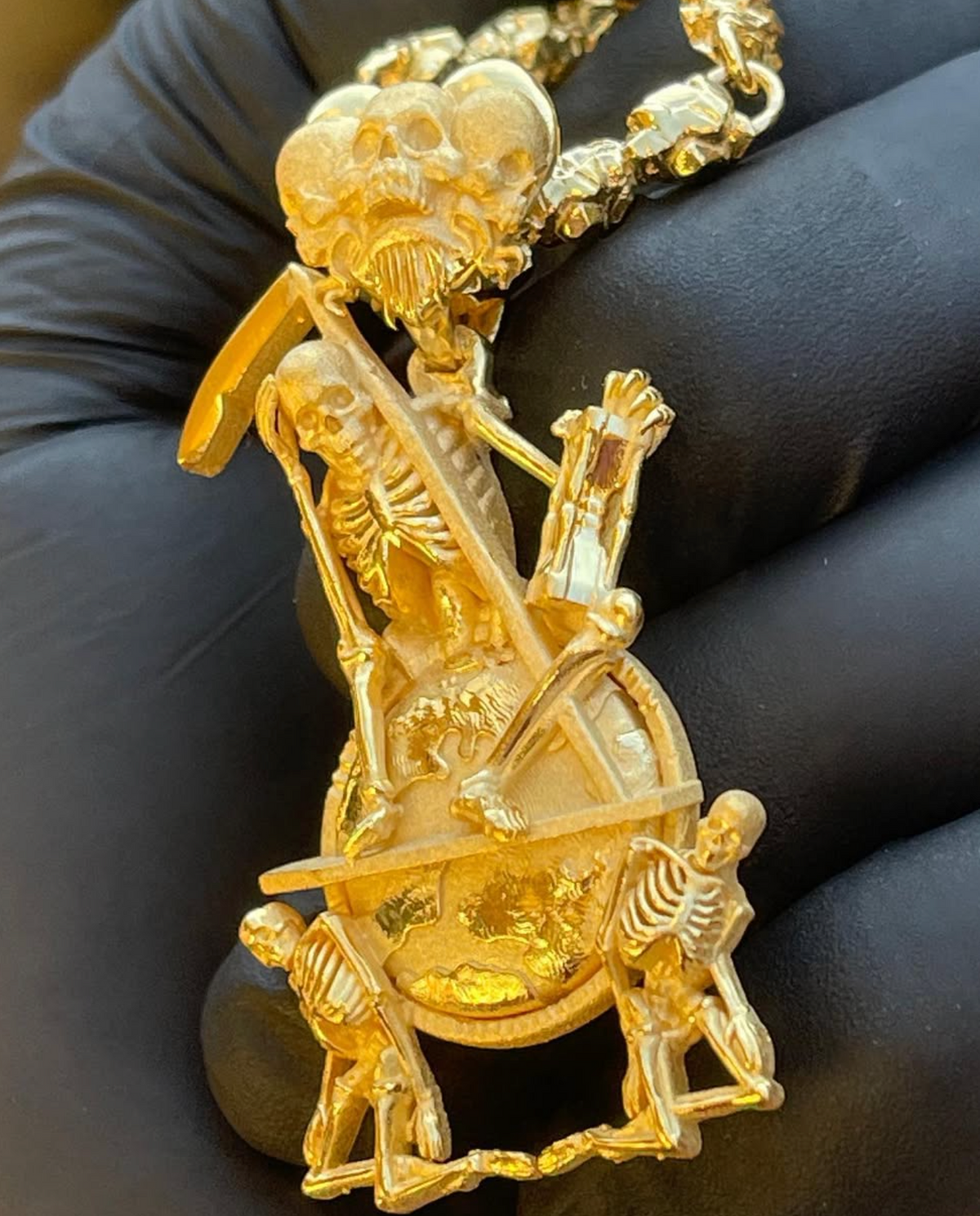 Memento mori gold pendant detail, mirror-polished scythe blade and carved ribcage