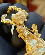 Memento mori gold pendant detail, globe with raised continents and skeletons clambering below