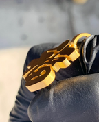 Fu good fortune gold pendant, edge view showing the thickness of the plate and polished cut edges