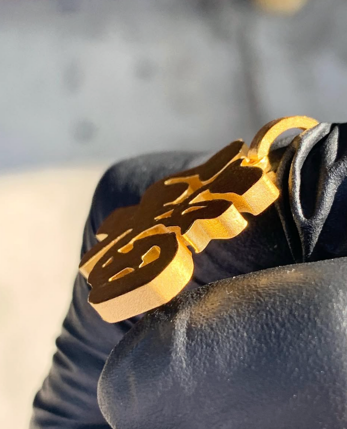 Fu good fortune gold pendant, edge view showing the thickness of the plate and polished cut edges
