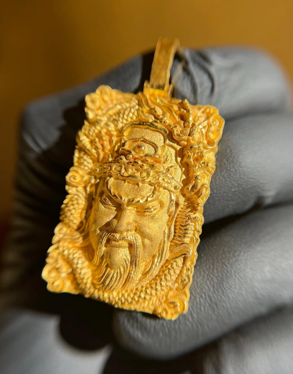 Guan Gong Face gold pendant, close view of the satin face against the polished stepped crown