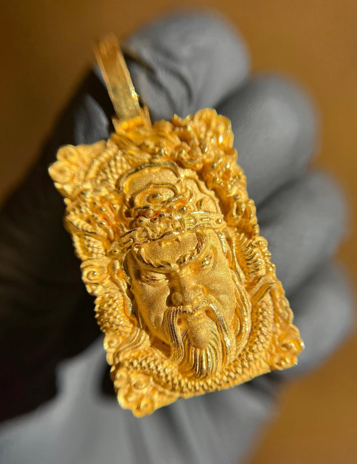 Guan Gong Face gold pendant, angled view showing the beaded band at the lower edge