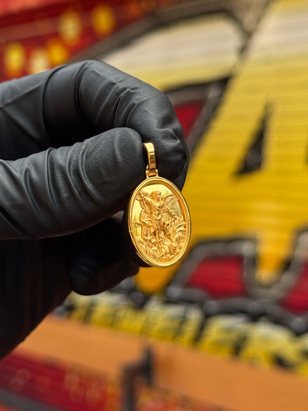Saint Michael Oval gold pendant photographed in hand