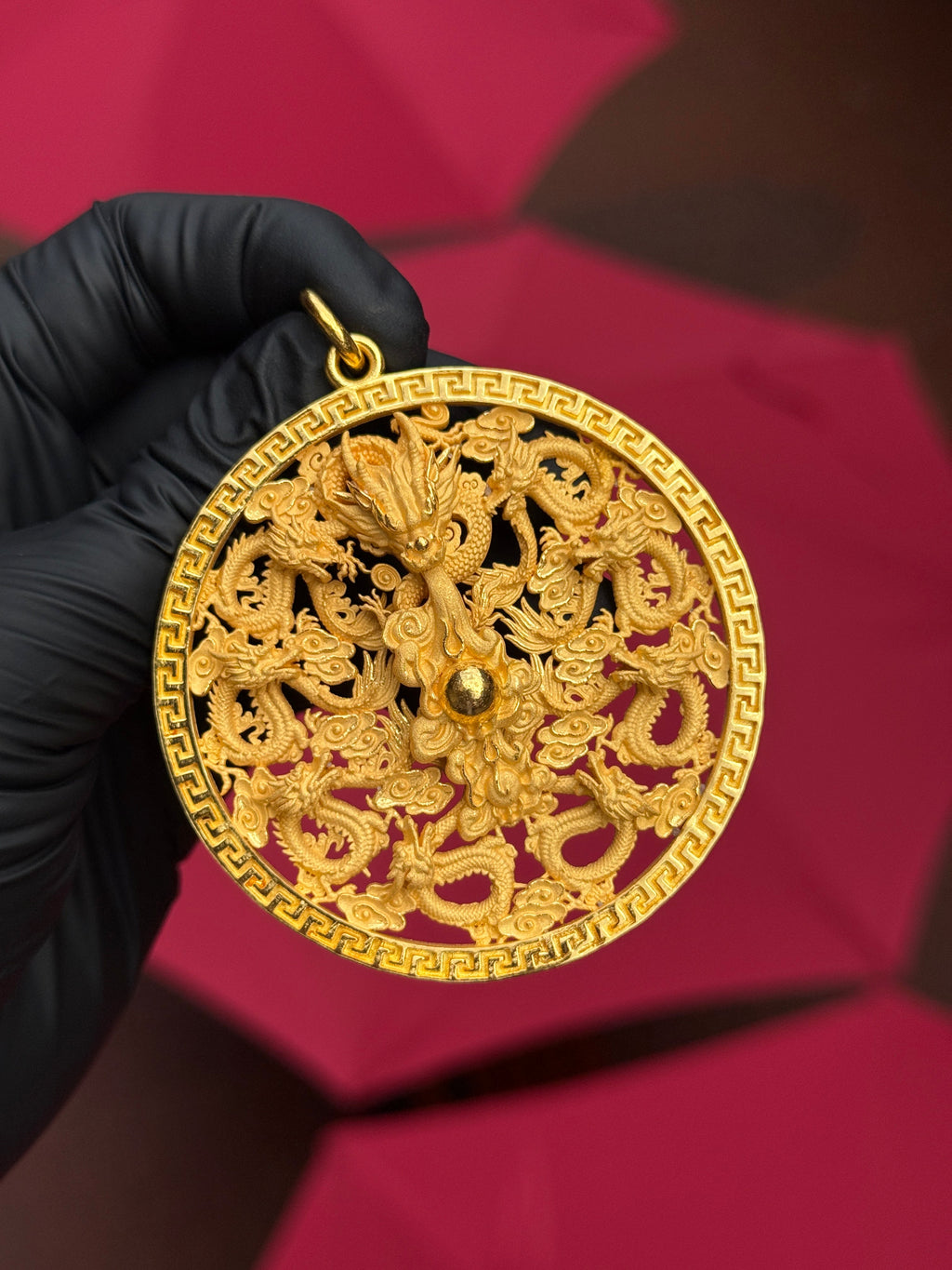 Medium 9 Dragons Circle gold pendant photographed against a red ground
