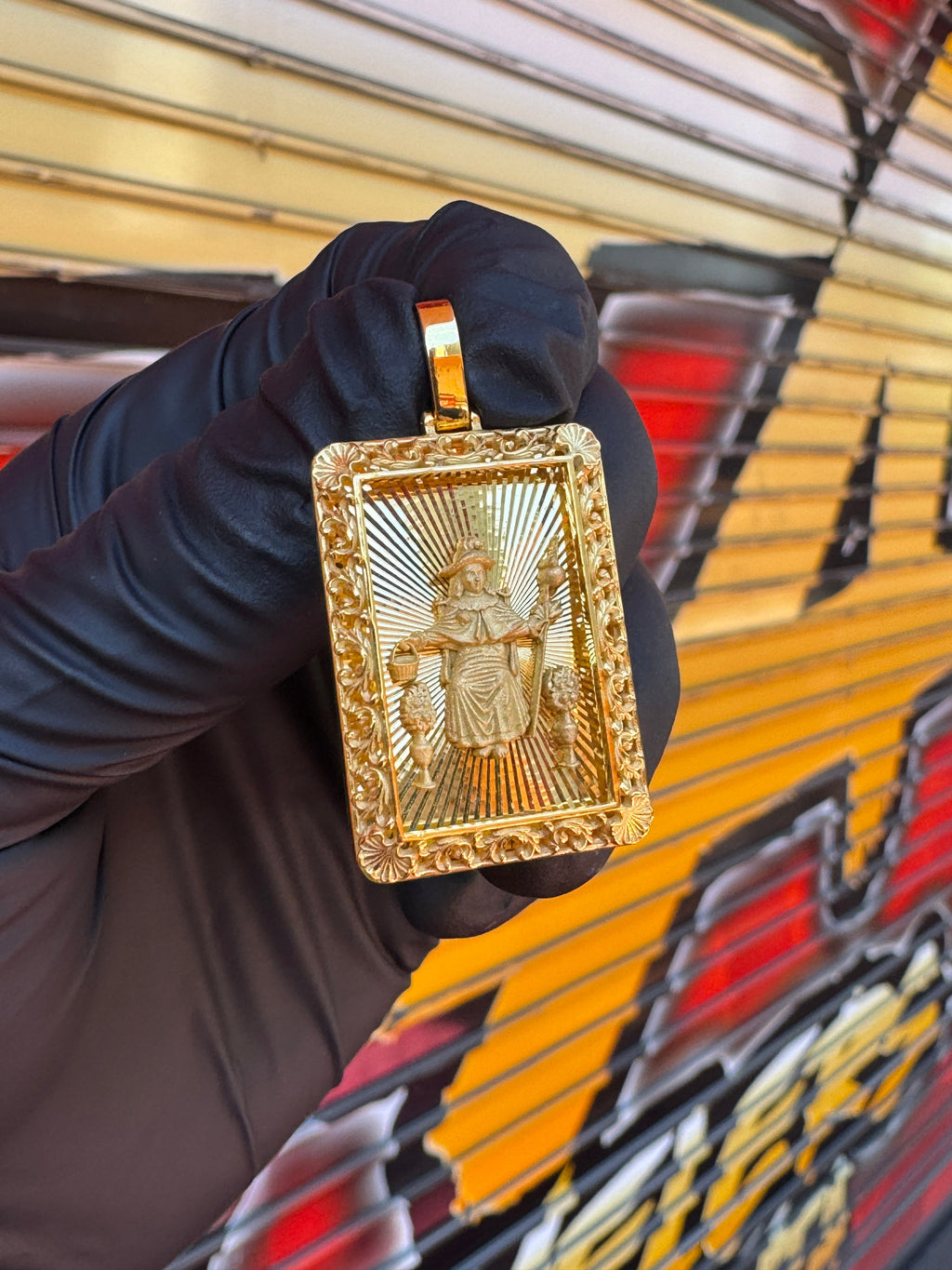 Diamond-Cut Santo Nino filigree border gold pendant photographed in hand