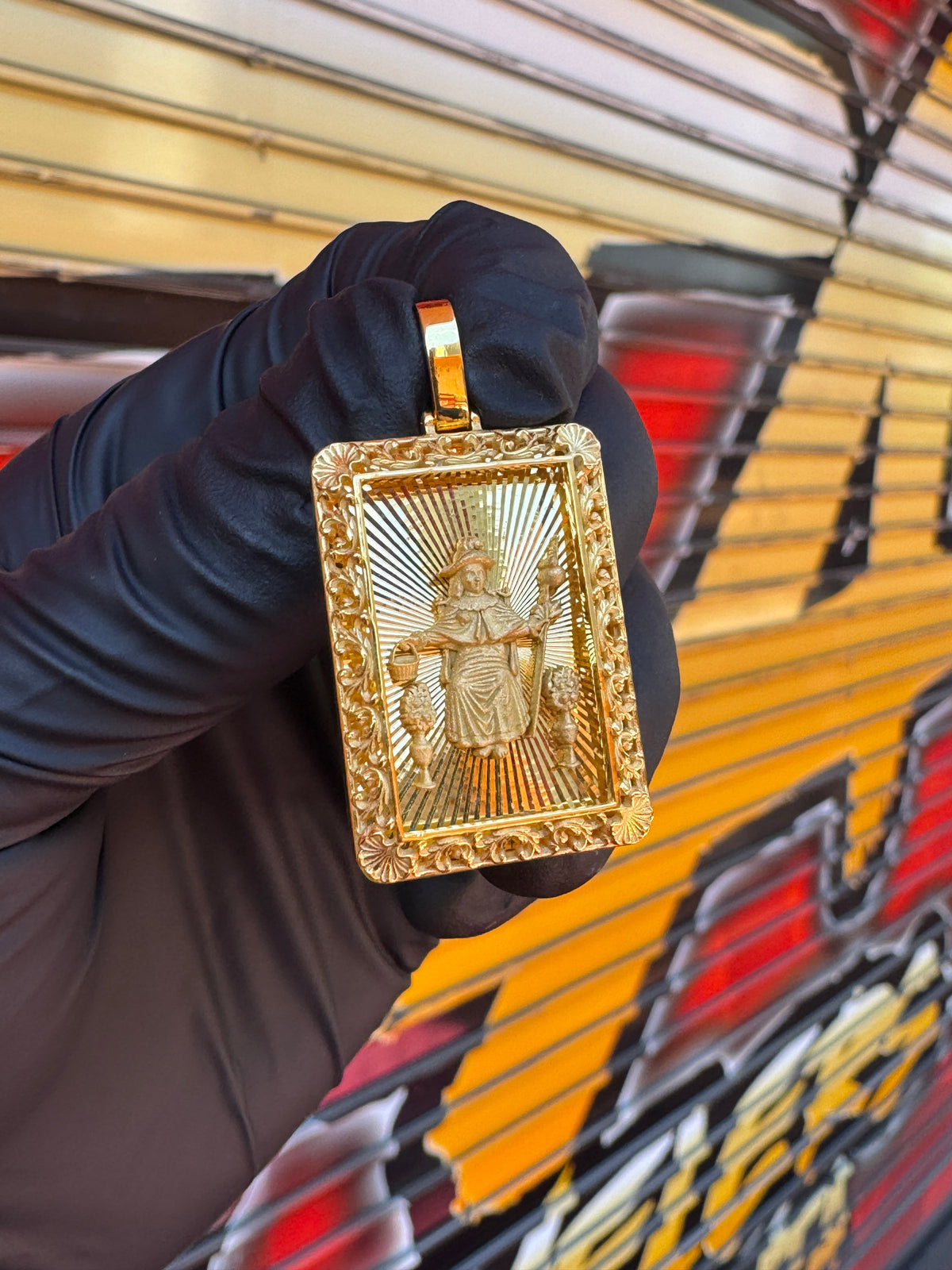 Diamond-Cut Santo Nino filigree border gold pendant photographed in hand