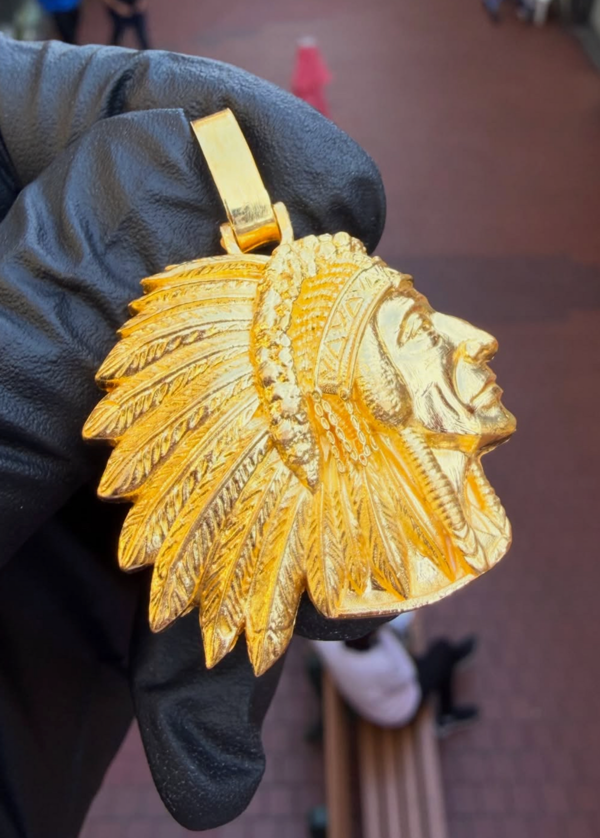 Gold Native American chief pendant, profile portrait under a full feathered war bonnet