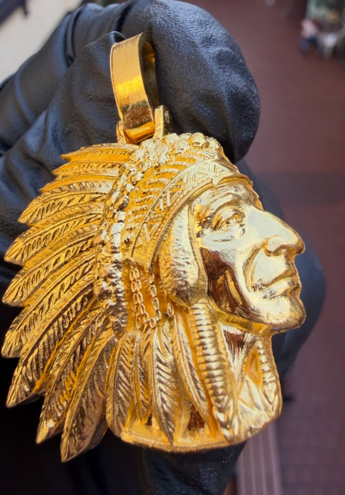 Native American chief gold pendant, angled view showing individually carved feathers