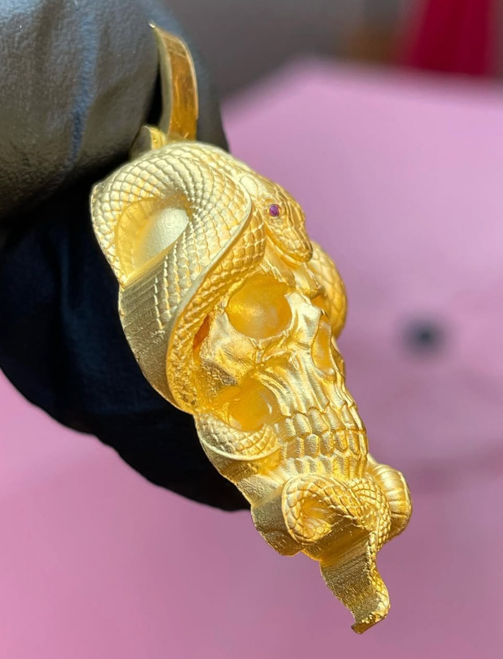 Skull and snake gold pendant detail, individually cut scales and the tail curling free below the jaw