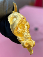 Skull and snake gold pendant detail, individually cut scales and the tail curling free below the jaw