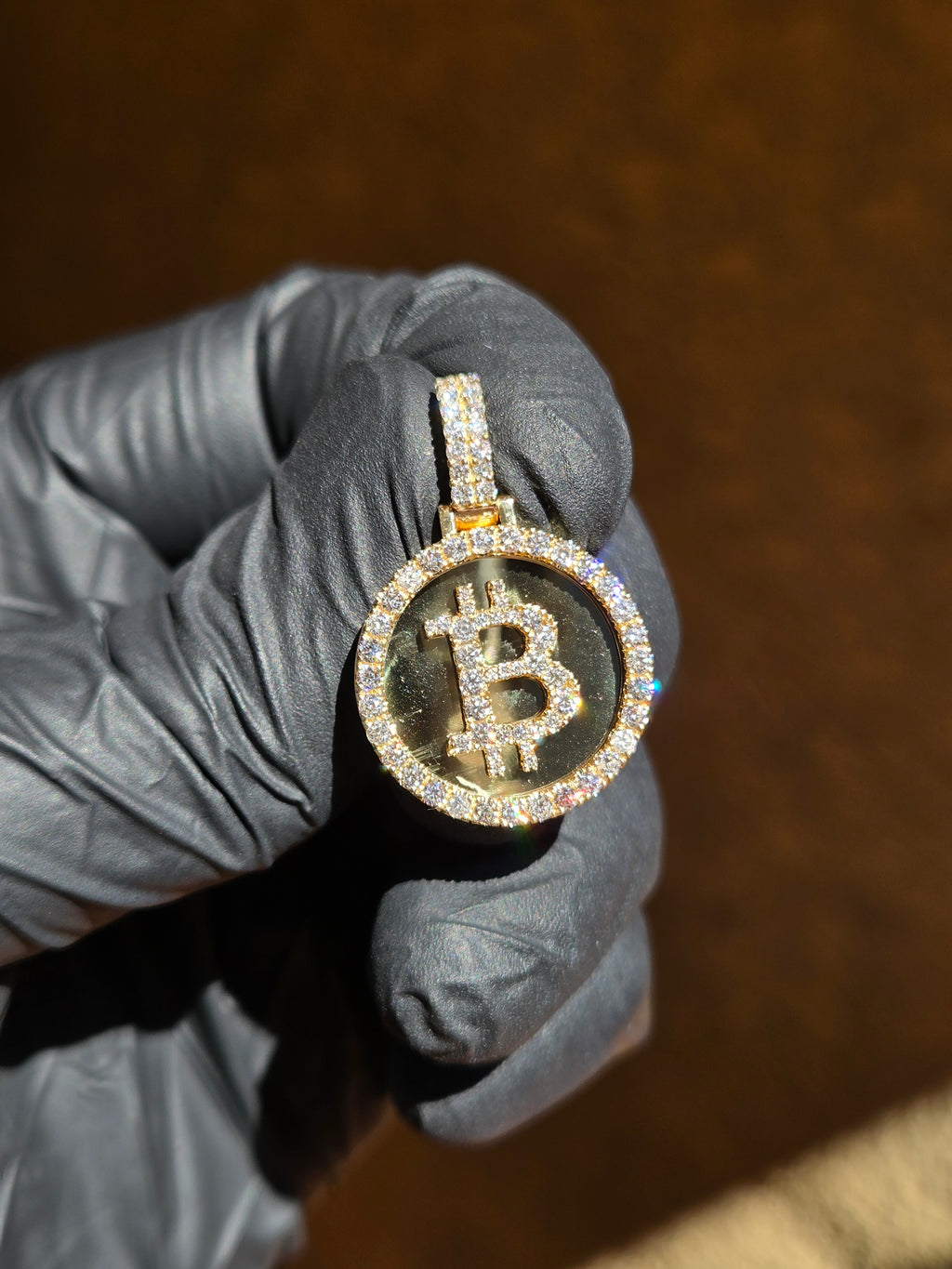 Bitcoin medallion in low light, the mirror field reflecting dark while the framed rim and the set symbol hold the light