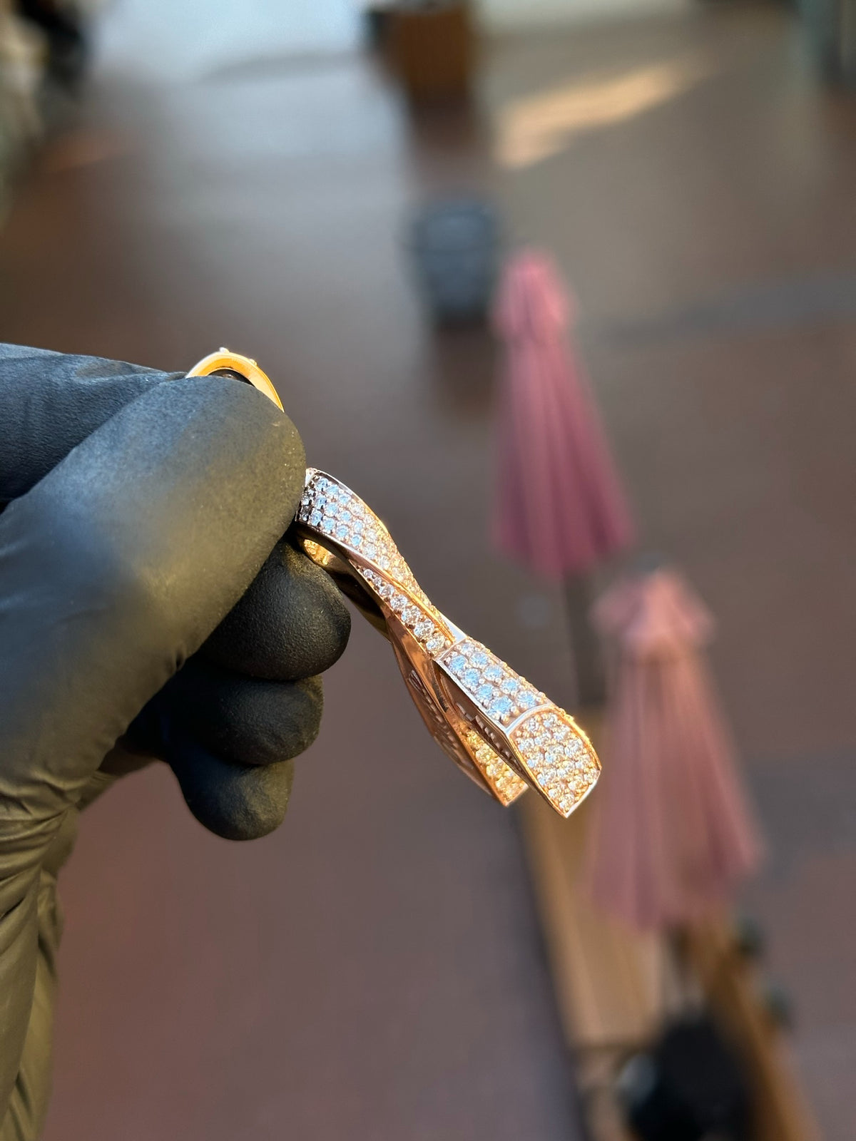 Angled view of the Cancer Ribbon Diamond Pendant showing the raised polished crossing lifting over the pave and the tapered stone rows.