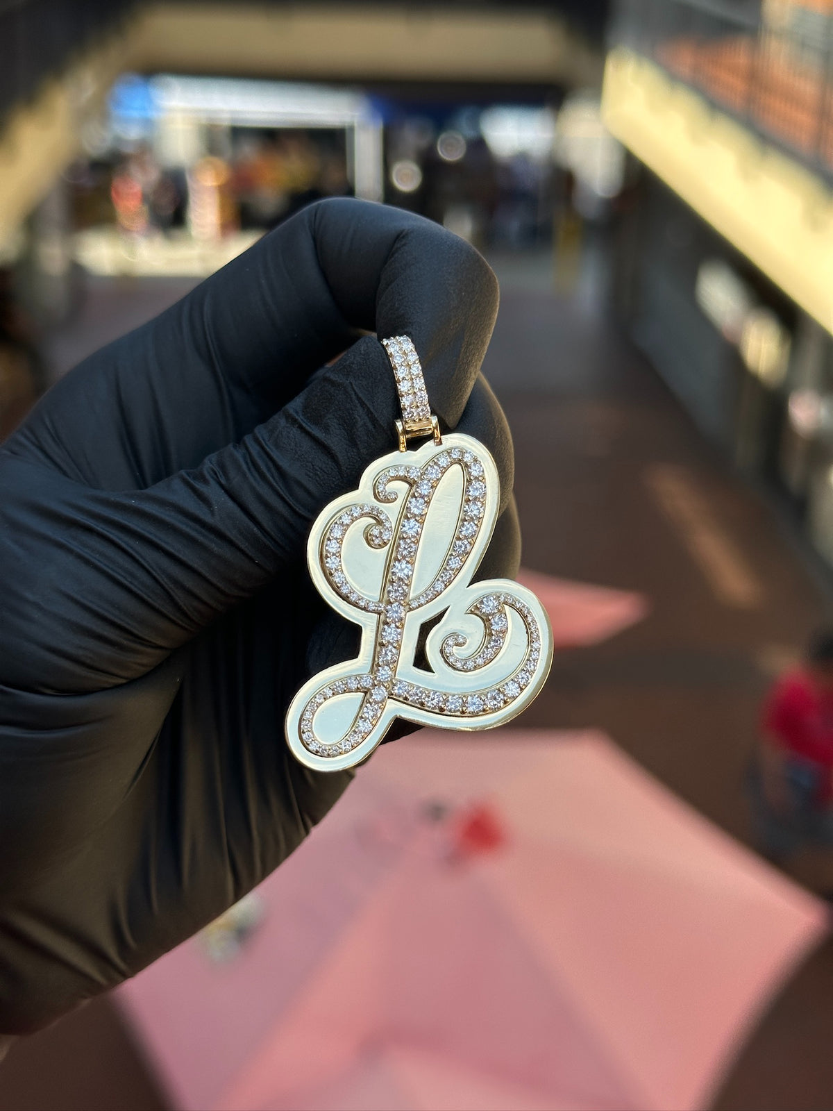Cursive L diamond pendant, polished gold panel behind the pave script, with a pave-set bail