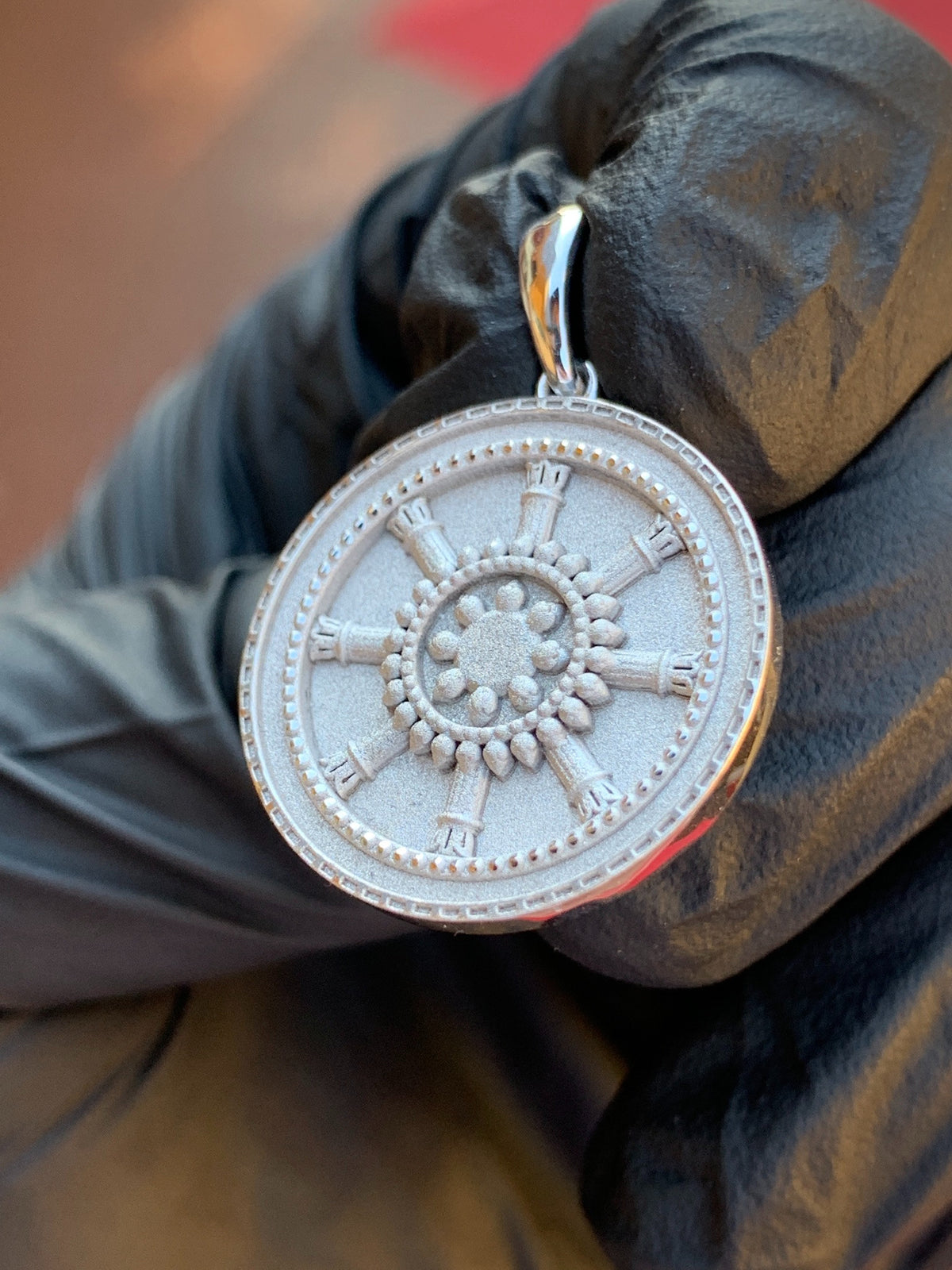 Close view of the Dharma Wheel Circular Pendant showing the sandblasted matte face, the raised teardrop petals at the hub and the beaded and milgrain borders.