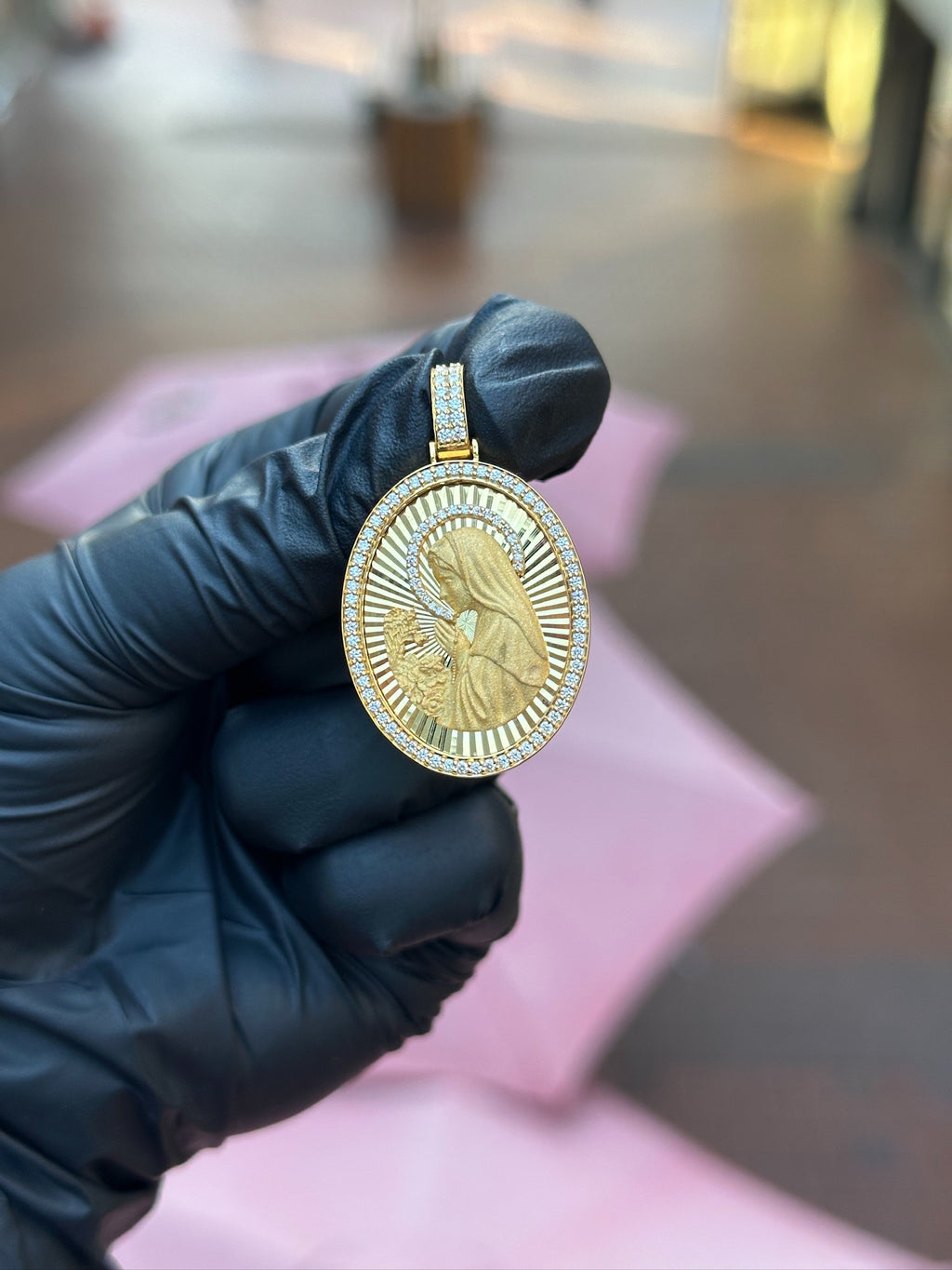 Double-sided diamond oval pendant in gold, two-row pave bail above pave-framed carved faces
