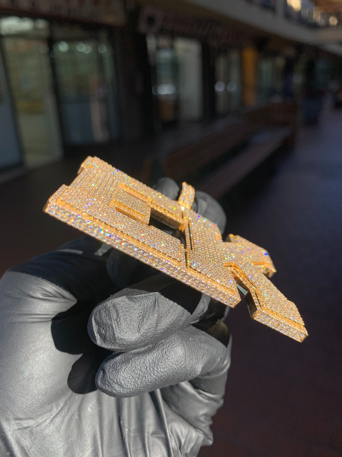 Edge view of the "EK" Diamond Pendant showing the full depth of the letters and the diamonds set across the side walls.
