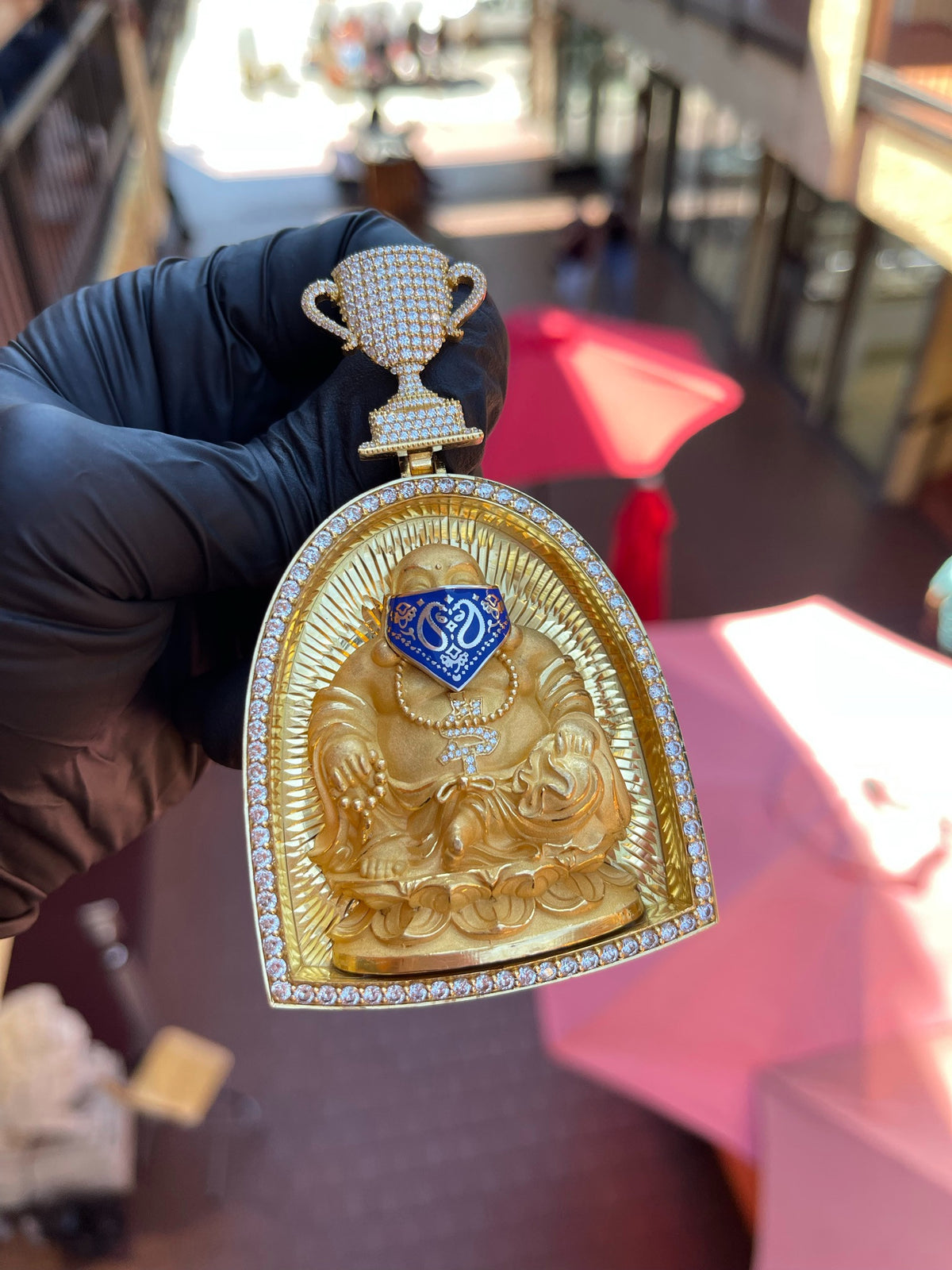 Daylight view of the Happy Buddha with a Bandana Arch Frame Diamond Pendant showing the sunburst-cut ground behind the figure and the full round of diamonds on the arch.