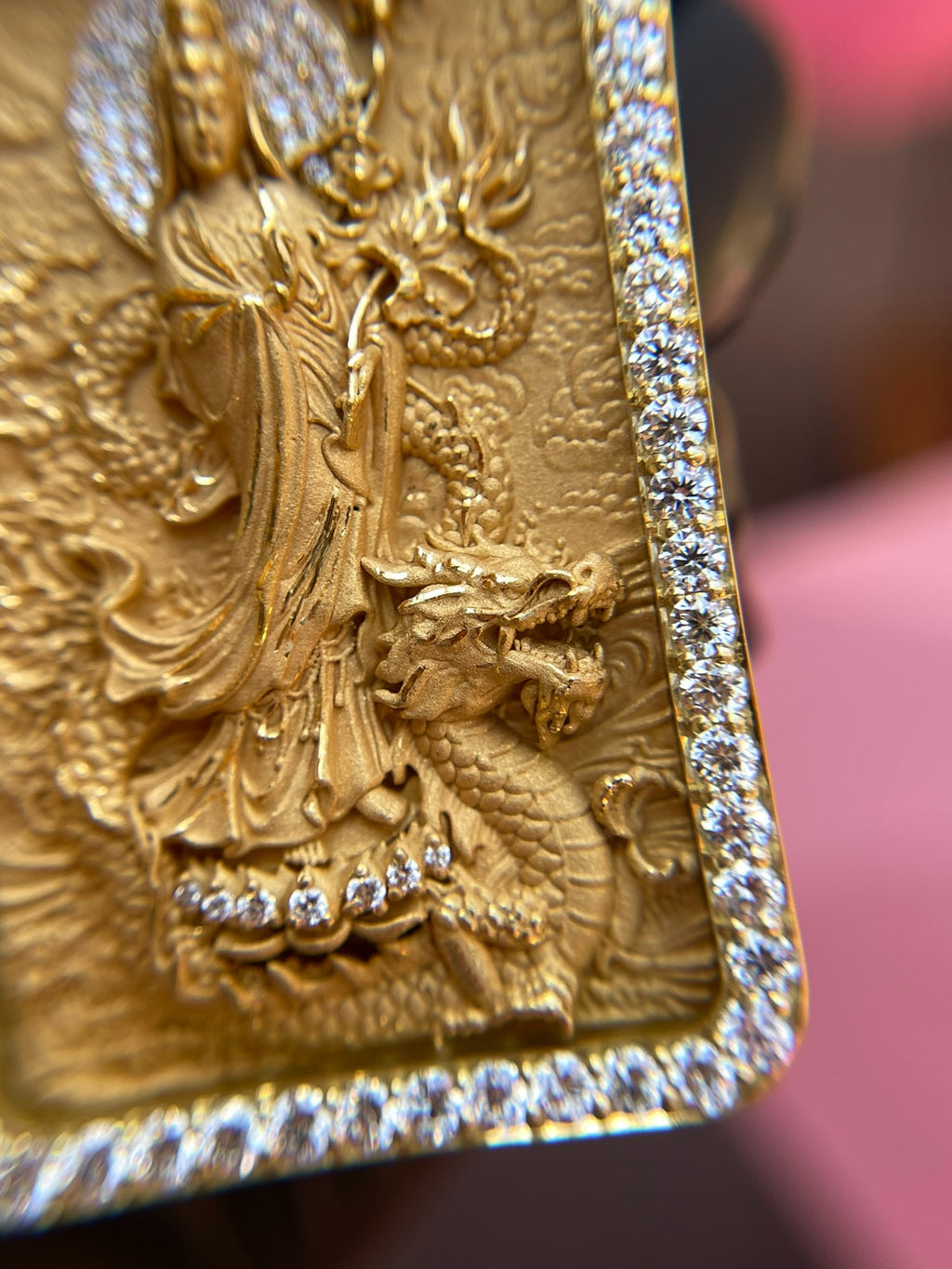 Corner detail of the Lady Buddha (Guan Yin) Diamond Framed Pendant showing the carved dragon coiling up the right side of the plaque against the prong-set frame.