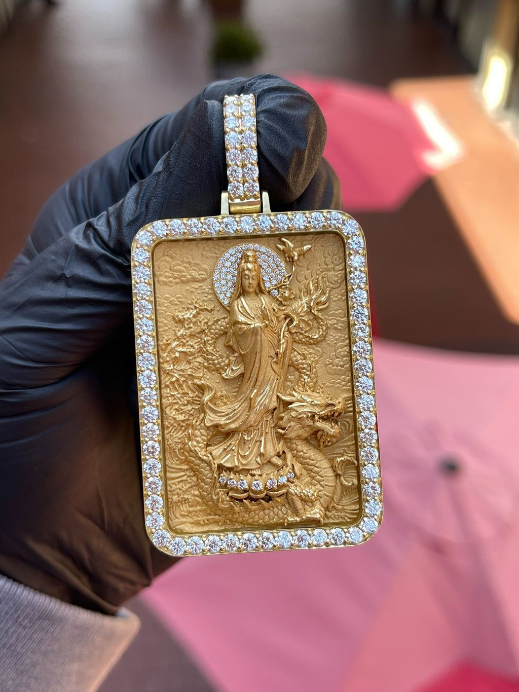 Full front view of the Lady Buddha (Guan Yin) Diamond Framed Pendant held in daylight, showing the complete diamond frame and the multi-row pave bail. Chain not included.