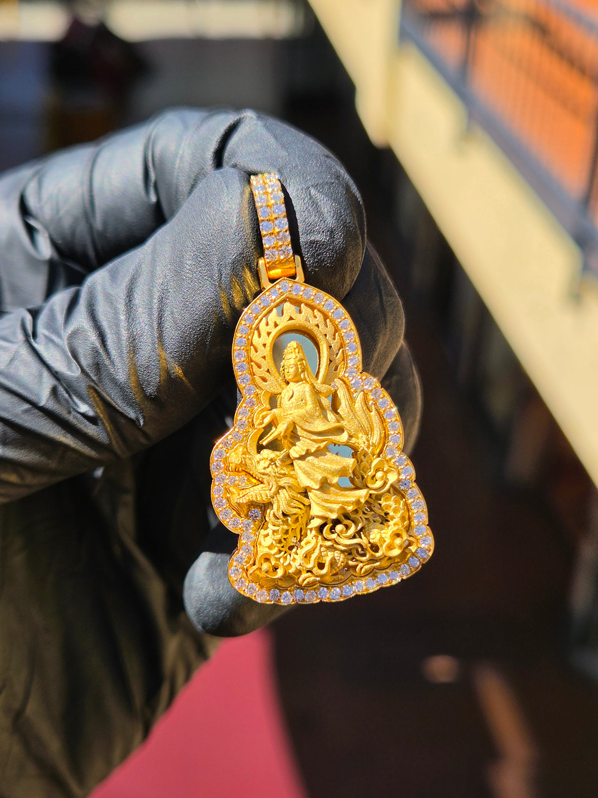 Guan Yin Riding a Dragon gold pendant in sunlight, lotus-bud tablet with a pierced flame mandorla and a full diamond halo