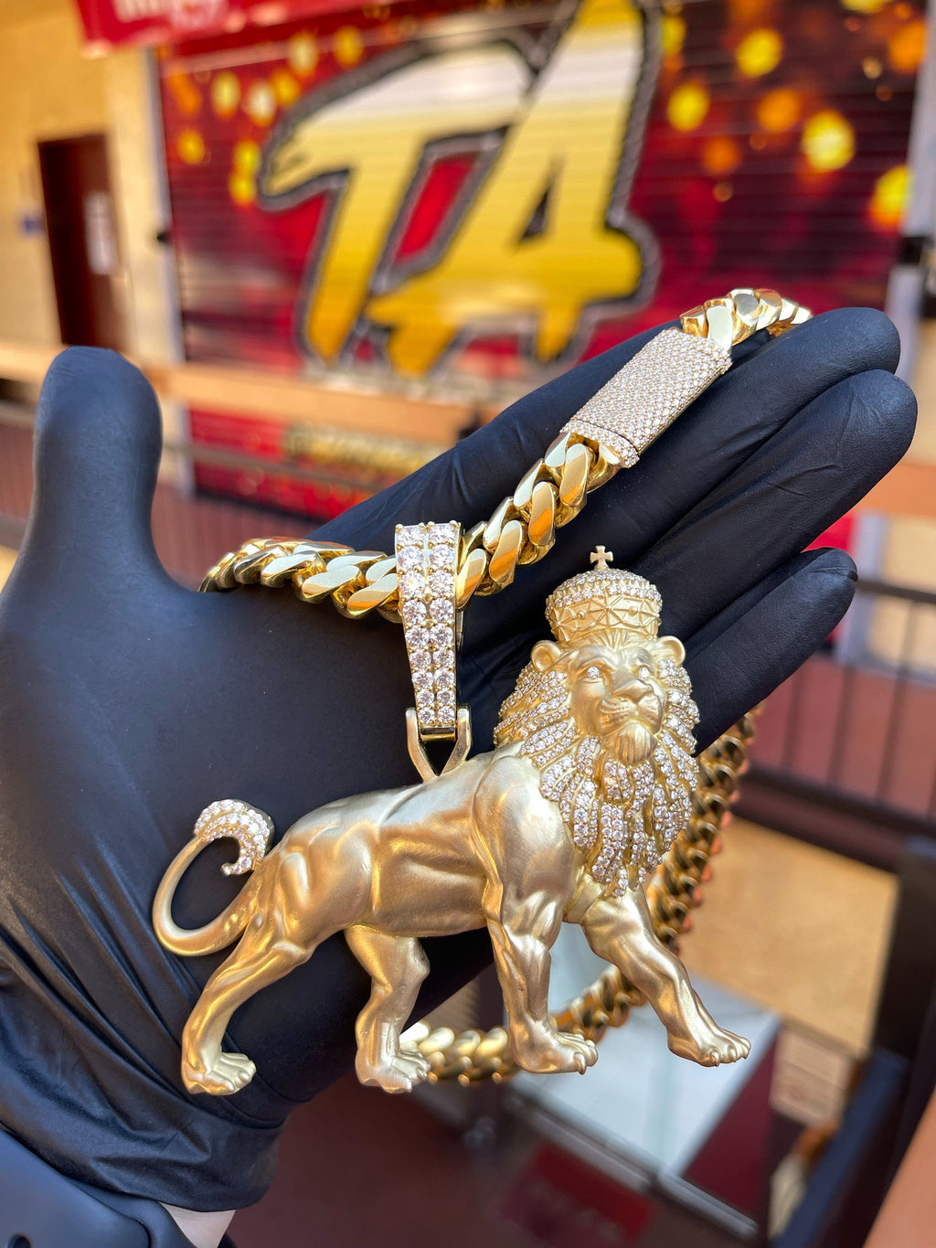 Yellow gold Large Lion Partial Diamond Pendant, a standing lion in satin gold with the mane, crown and tail tip pave-set in diamonds, shown on a Cuban link chain.