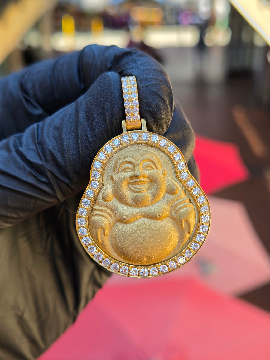 Medium Happy Buddha diamond pendant in shade, arms raised and eyes creased shut inside a recessed field and polished frame