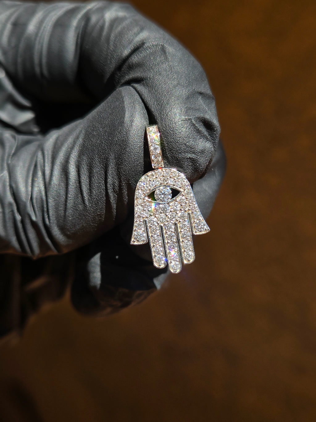Mini Hamsa diamond pendant in sunlight, the hand pave-set edge to edge with a marquise eye cut through the palm