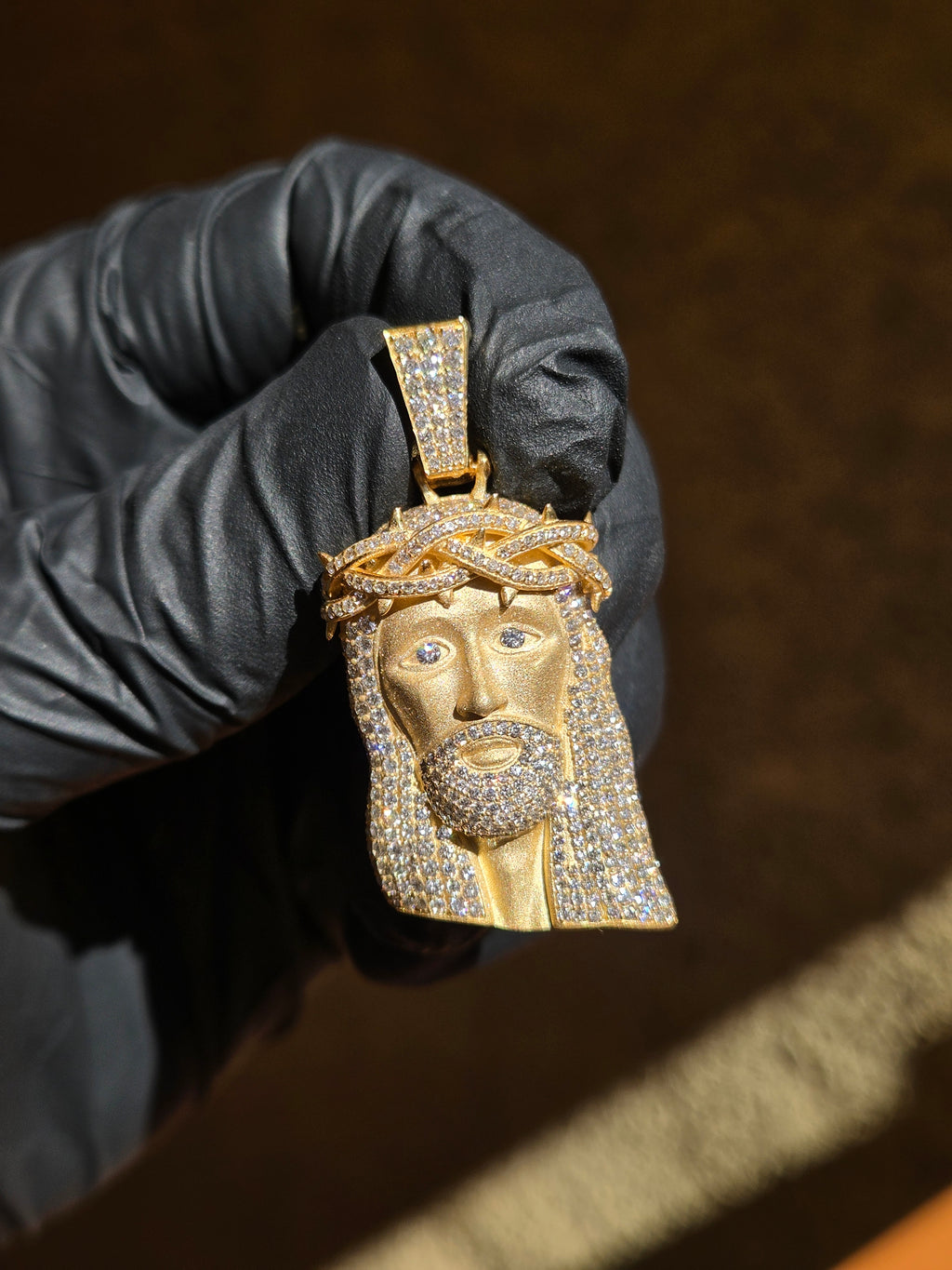 Partially Iced Diamond Jesus V2 gold pendant, hair and beard set solid with diamonds against a bare sandblasted face
