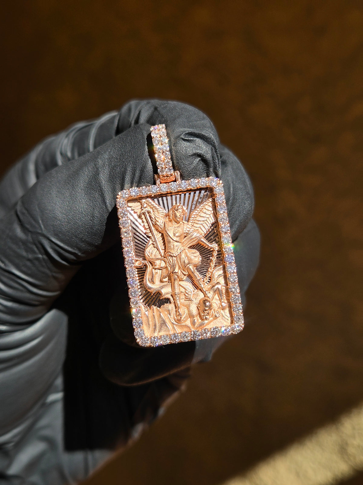 Saint Michael Archangel gold pendant in sunlight, full wingspan over a diamond-cut ray field inside a frame of large round diamonds
