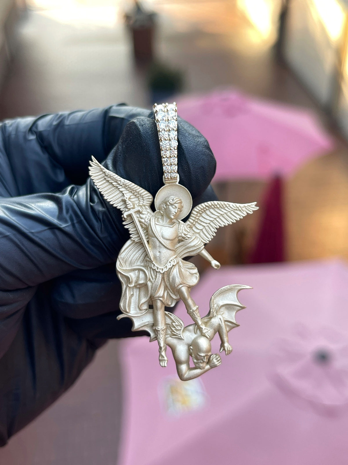 White gold Saint Michael Archangel Silhouette Pendant, the archangel cut free with both wings open and a spear driven into the figure beneath, on a two-row pave bail.