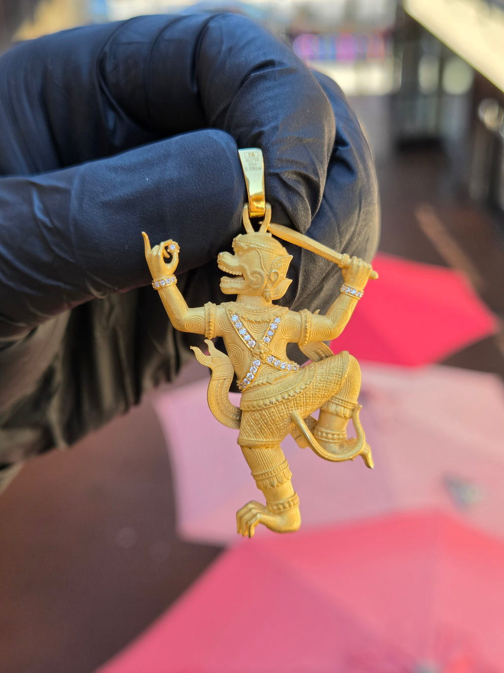 Thai Hanuman pendant held to show the bail, with the crossed diamond chest bands and engraved spiral ornament across the body