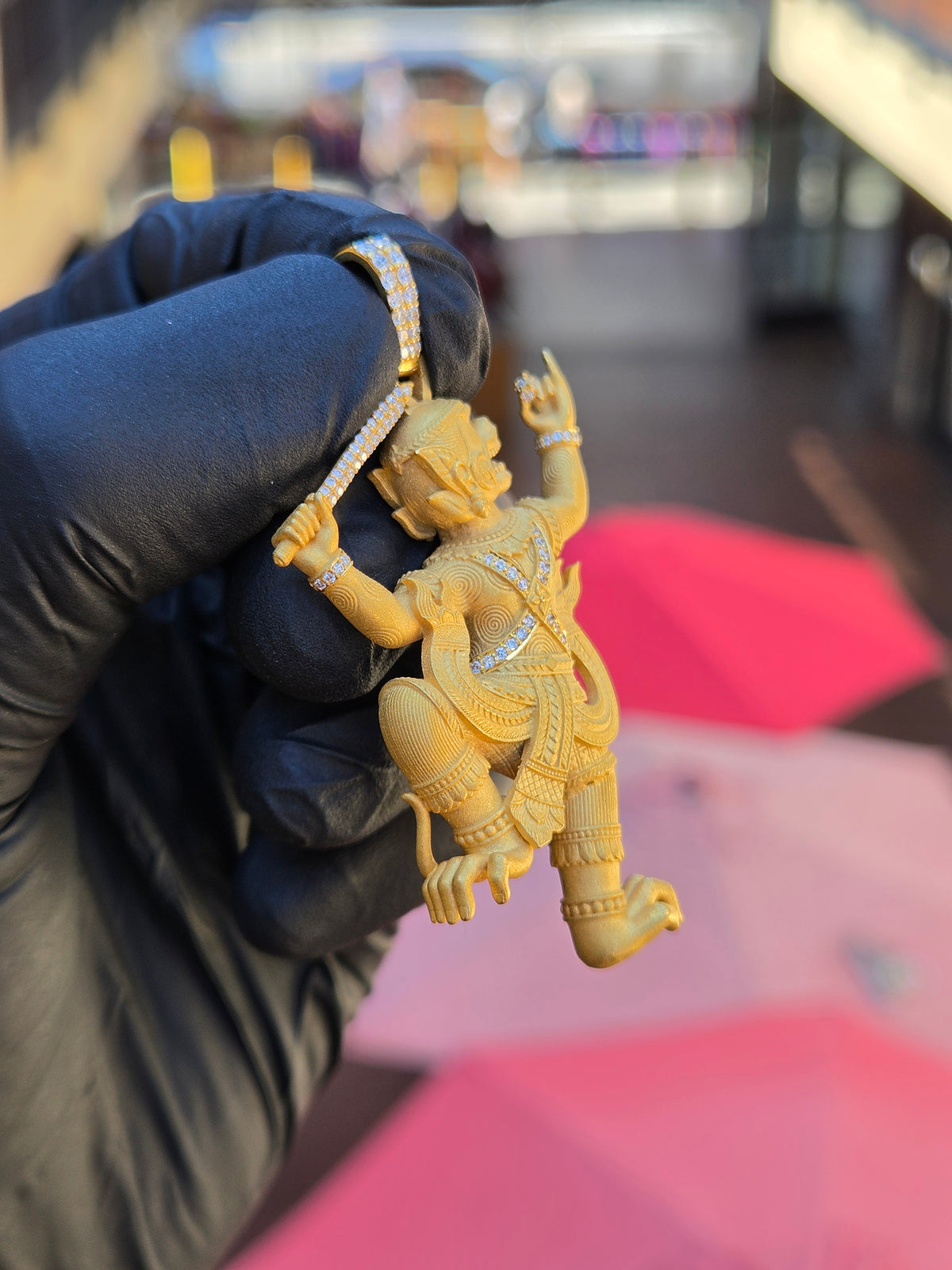 Angled view of the Thai Hanuman pendant showing it is carved fully in the round, with the trailing foot and scarf ends free in the air